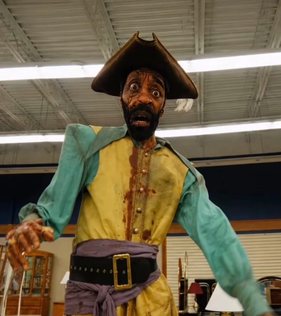Pirate Clark from Backrooms (2026), a grotesque larger-than-life caricature of Clark dressed as a pirate wearing a tricorn hat